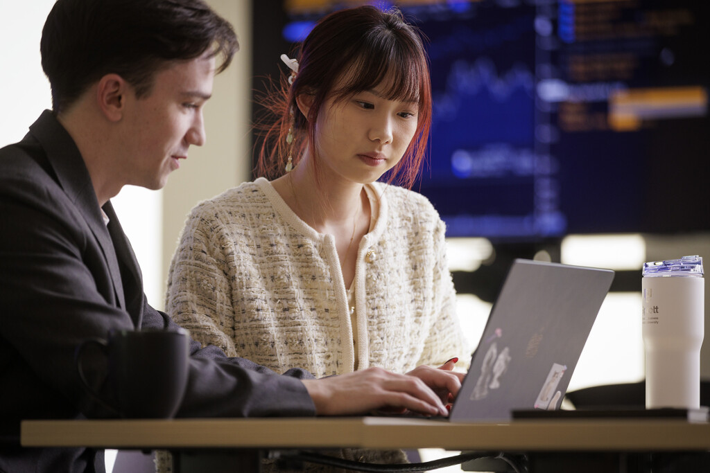 Master of Finance students working on a laptop with Bloomberg in the background in the Sprott School of Business at Carleton University in Ottawa, Ontario, Canada.