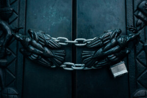 Dark gothic doors locked with heavy chains and a padlock.