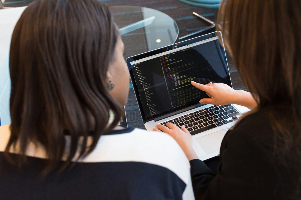 Two women coding on a laptop.