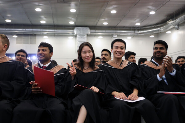 A group of Sprott School of Business graduates in regalia while sitting in rows at Carleton University convocation.