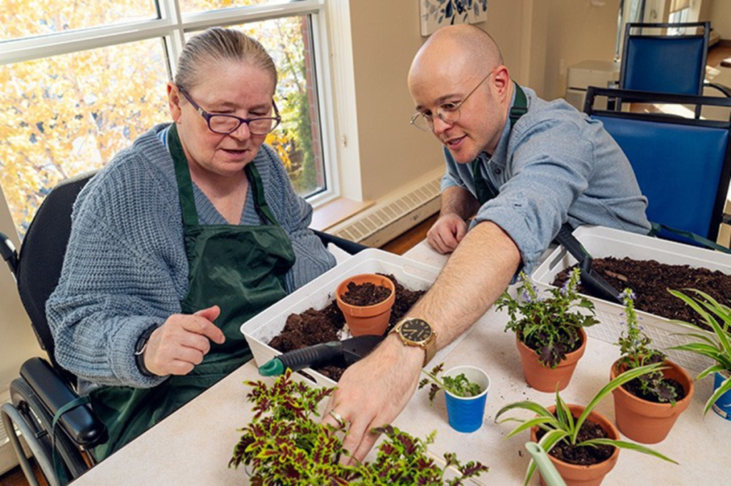 An activation aide works with a resident in assisted senior living on therapeutic horticulture.