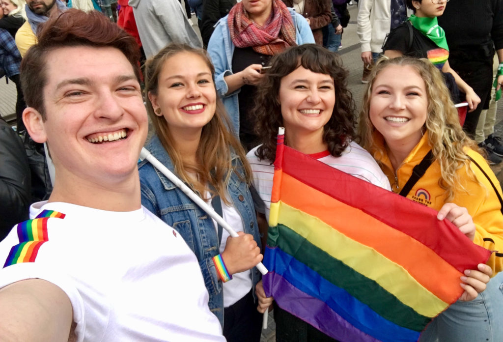 Alexa and her friends holding up a rainbow flag at the pride parade.