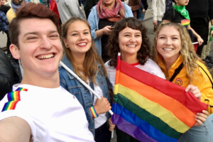 Alexa and her friends holding up a rainbow flag at the pride parade.