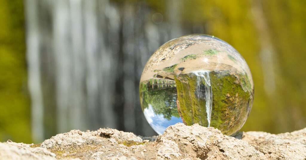 A picture of a glass ball with the waterfall behind it being reflected in it.