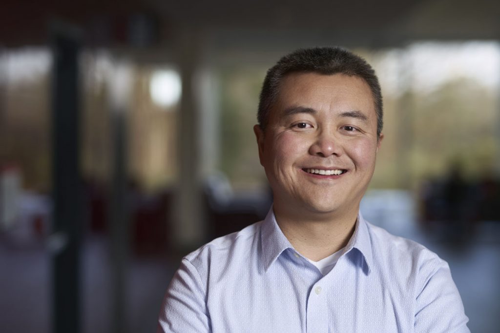 Frank Jiang smiling in a hallway