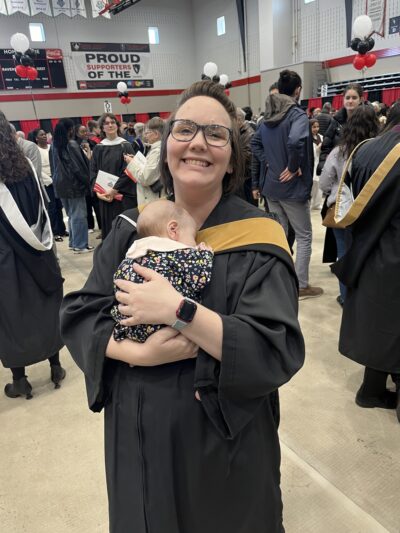 Sara Smith in graduation gown, holding her baby