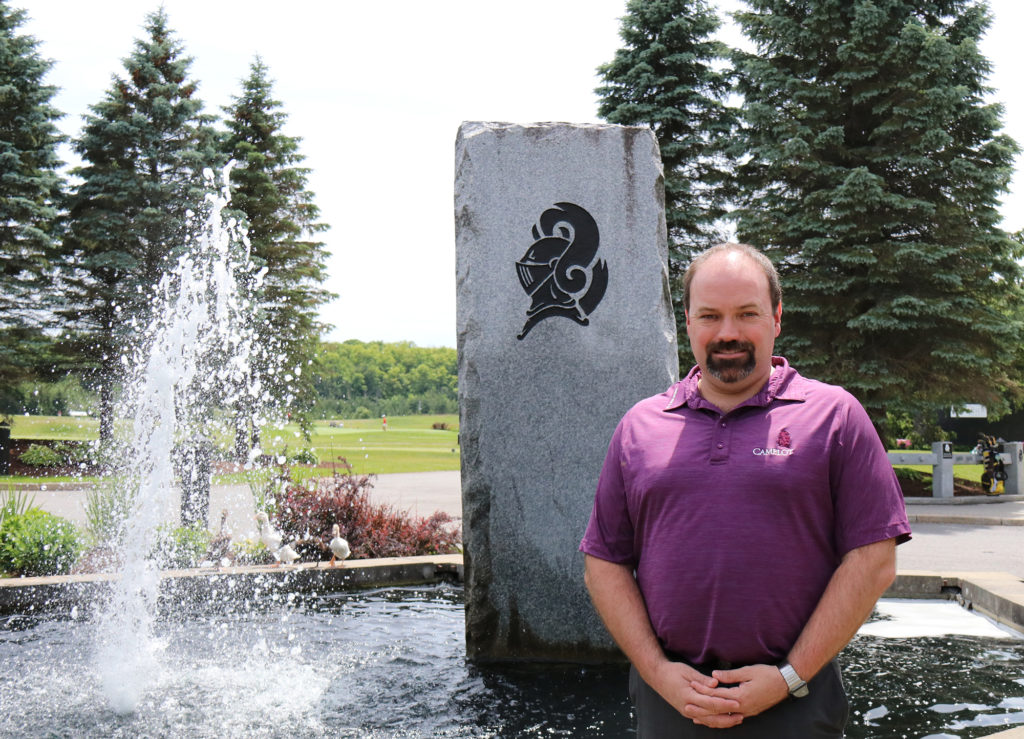 sprott alumnus Greg Richardson standing in front of a fountain at the golf club