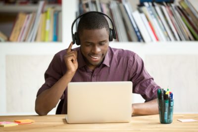 Picture of man talking into a laptop with his headphones on.