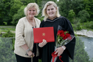 kayla maduk holding her diploma and flowers in her graduation gown with her mom