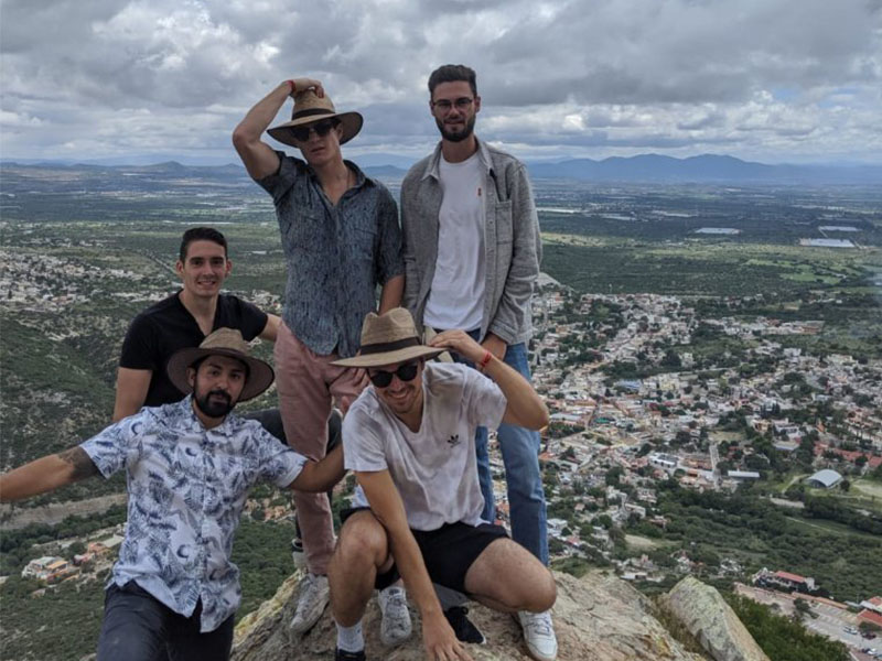 A picture of Jacob Sams and four of his friends on top of a high hill in San Miguel de Allende, Mexico. You can see a view of the city behind them. 