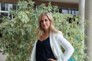 Leslie against a fern in a white jacket