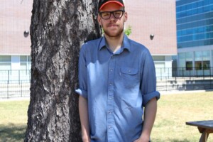 Liam leaning against a tree in the quad