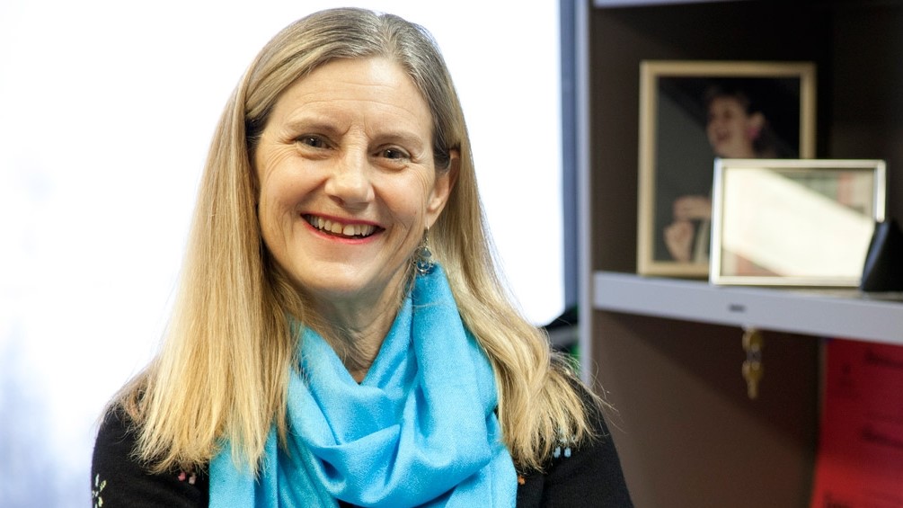 Linda Duxbury smiling in her office wearing a blue scarf