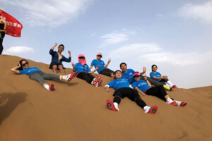 A team of students from Sprott's MBA cohort in Shanghai resting on a sand dune during the 2018 Asia-Pacific Business School Desert Challenge.