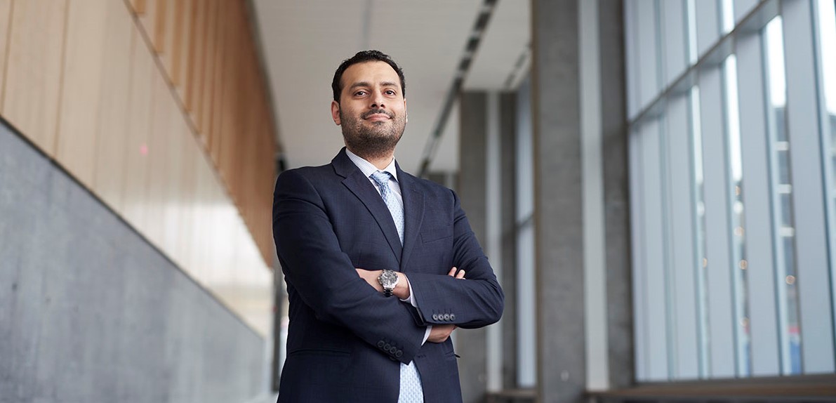 Mohamed Al Guindy standing in a hallway of windows with his arms crossed.