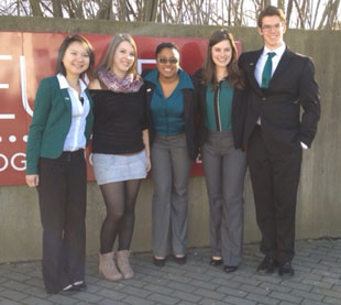 Mimi Lam, the host from Leuven, Stephaine Lawrence, Kendra Thorogood and Ross Park all dressed in black and green in front of the Leuven University sign in Belgium