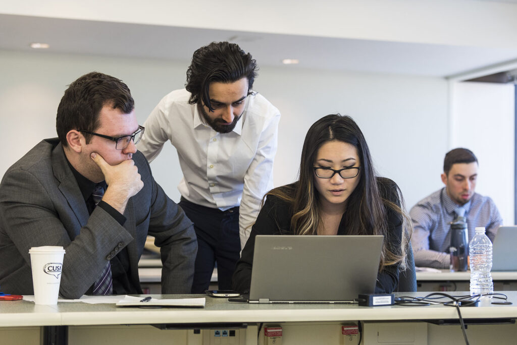 Diverse group of Sprott students working together on a project.