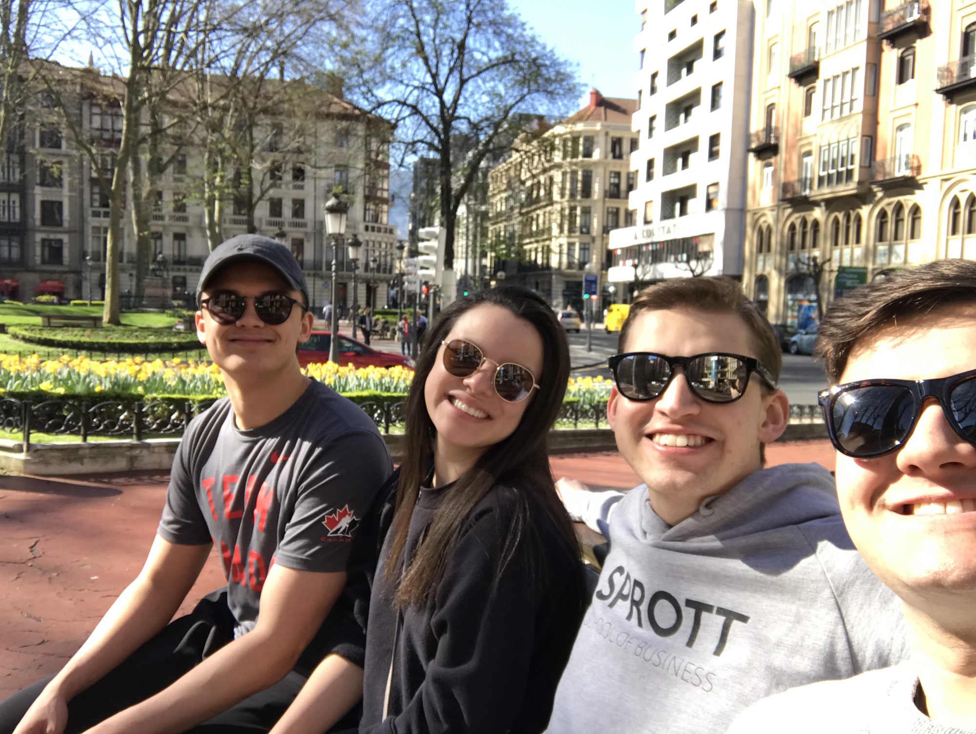 Harry with 3 other students sitting on a bench in Spain.