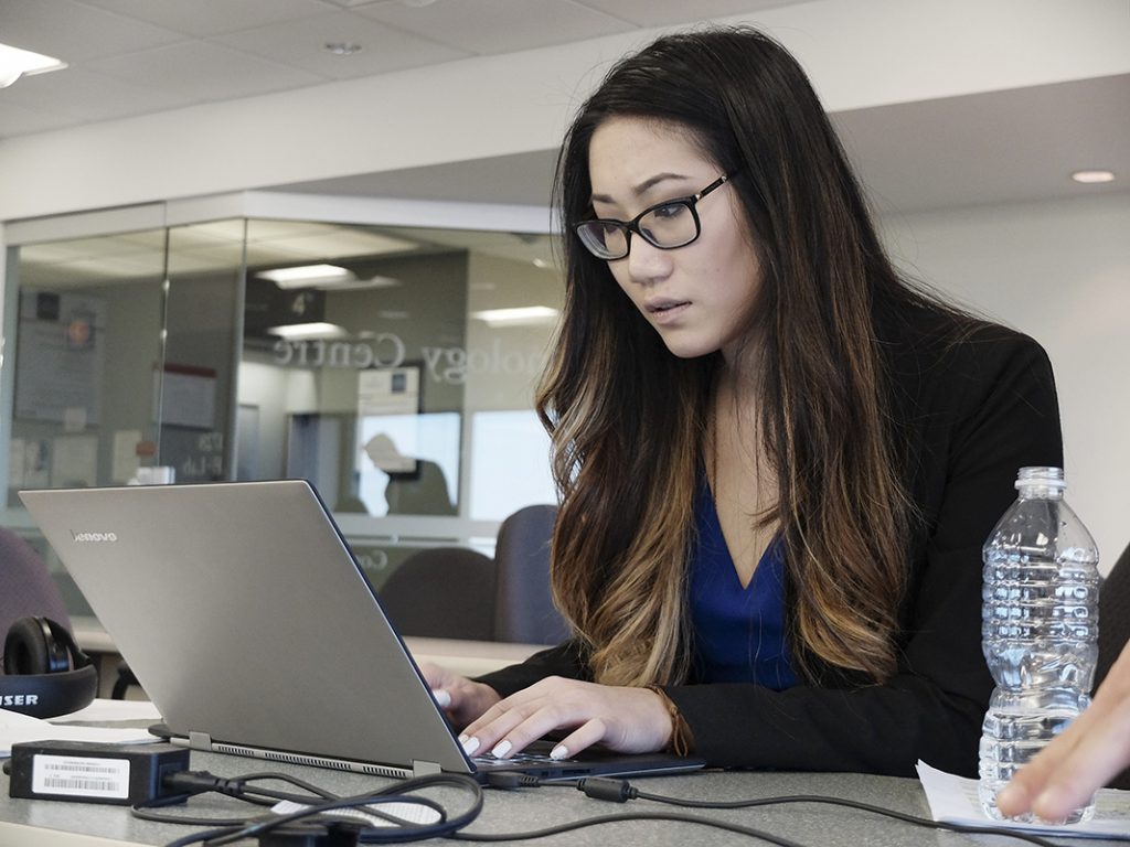 a female student in business attire at a laptop