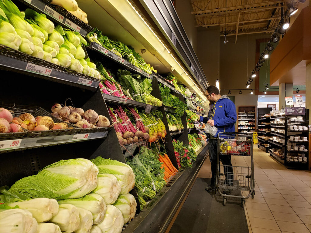 Male shopper looking at vegetable produce in a grocery store. 