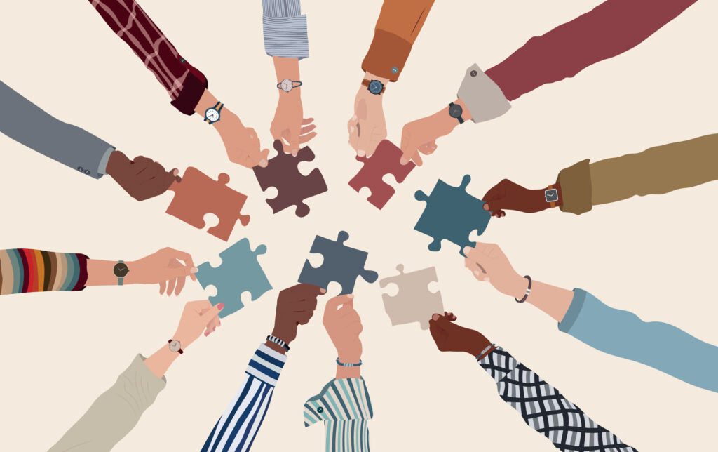 Group of multicultural business people with raised arms holding a puzzle piece.