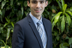 Jacob in a suit with grenery in the background.