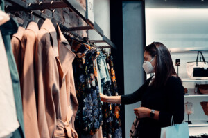 Female shopping wearing a mask in a clothing boutique.