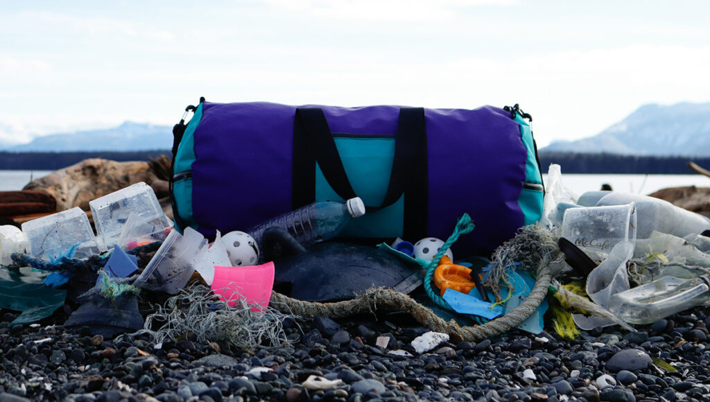 Duffle bad and broken outdoor gear on a beach.